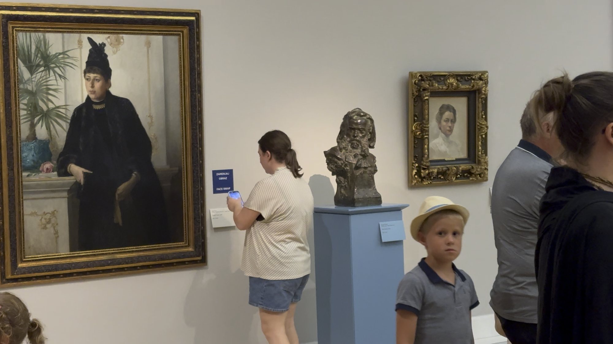 A visitor scanning the WONDERCUT QR code next to a portrait at the National Gallery of Slovenia