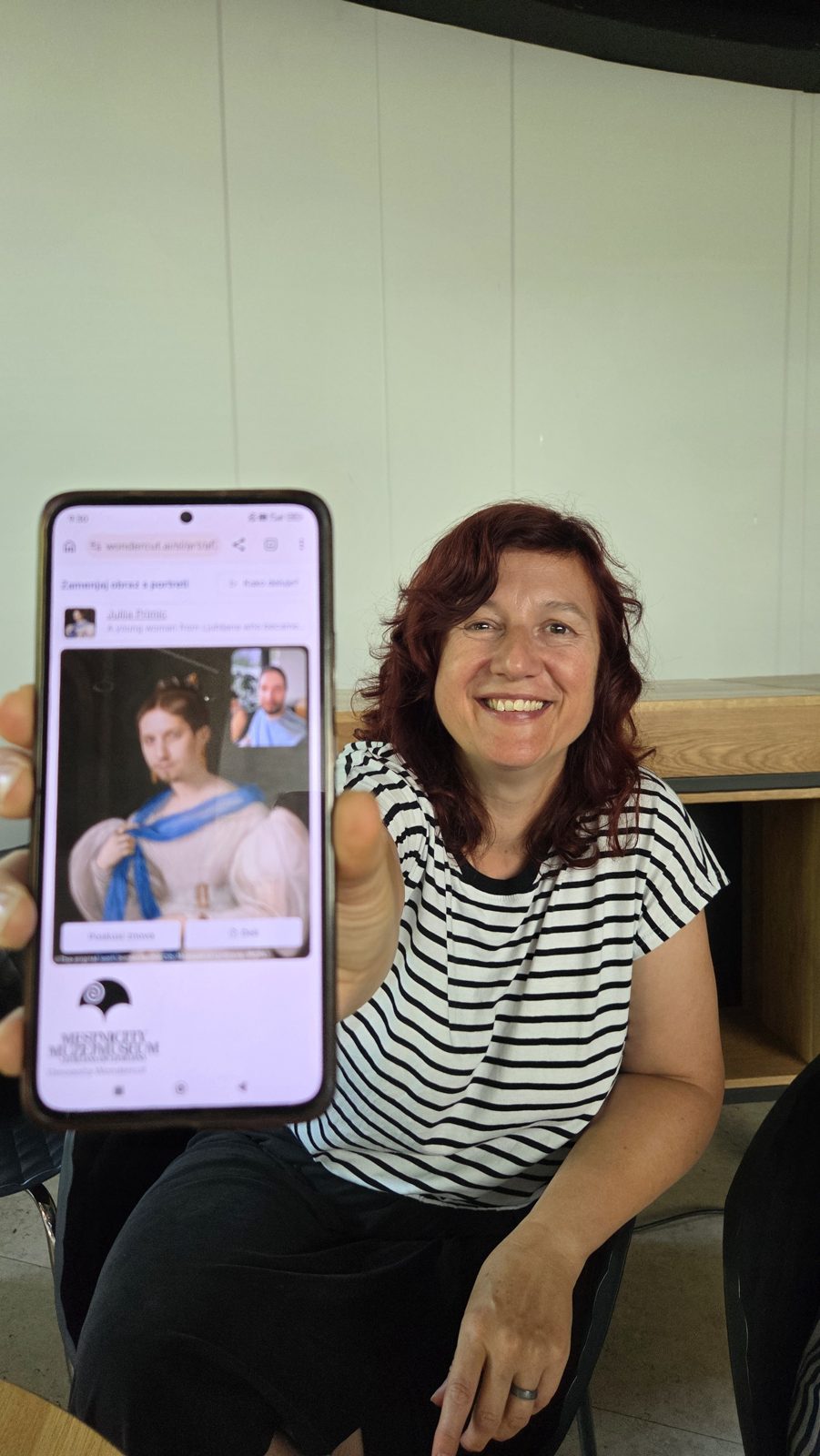 A participant smiling while holding a phone showing her AI-generated portrait